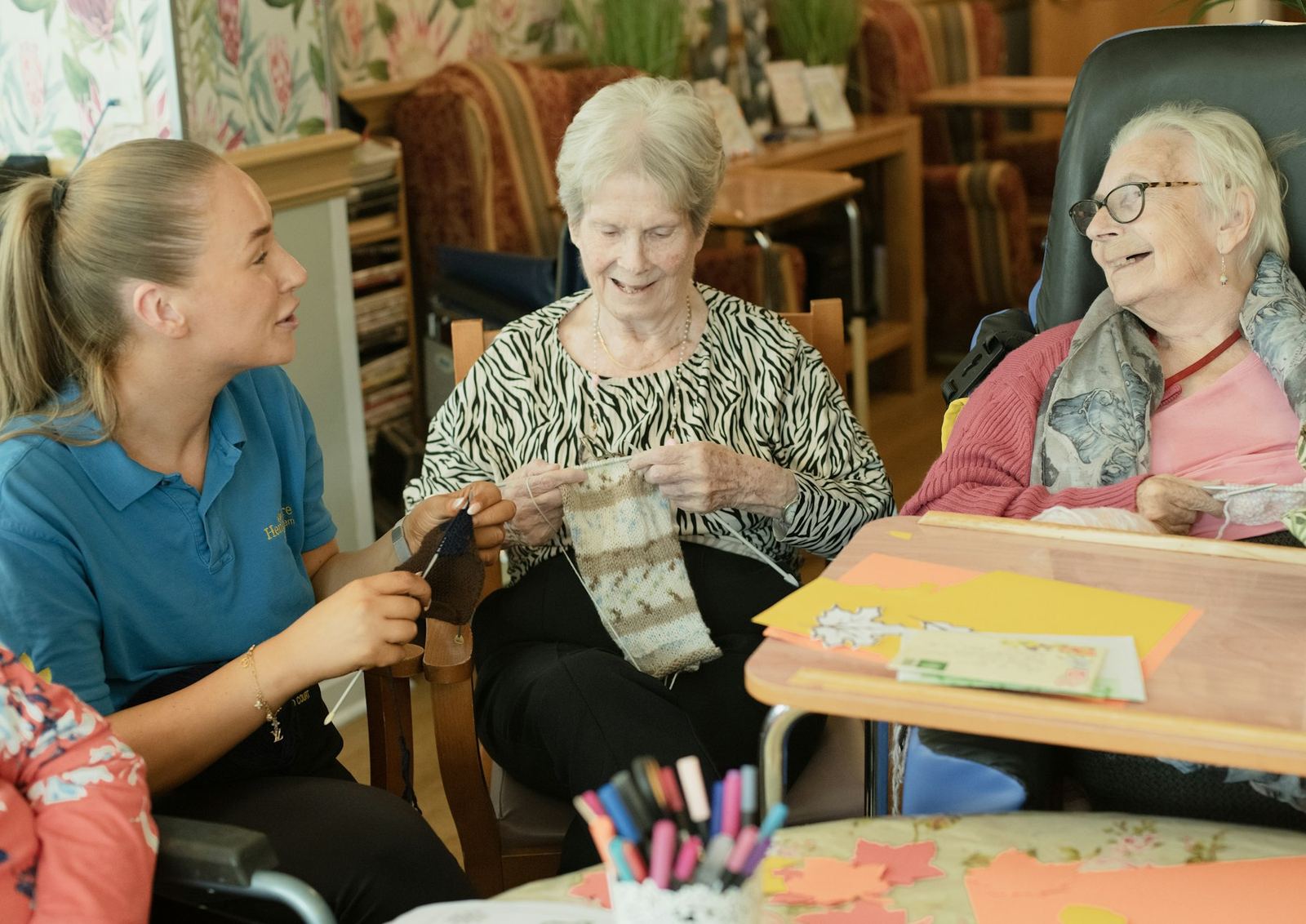 A caregiver with residents knitting