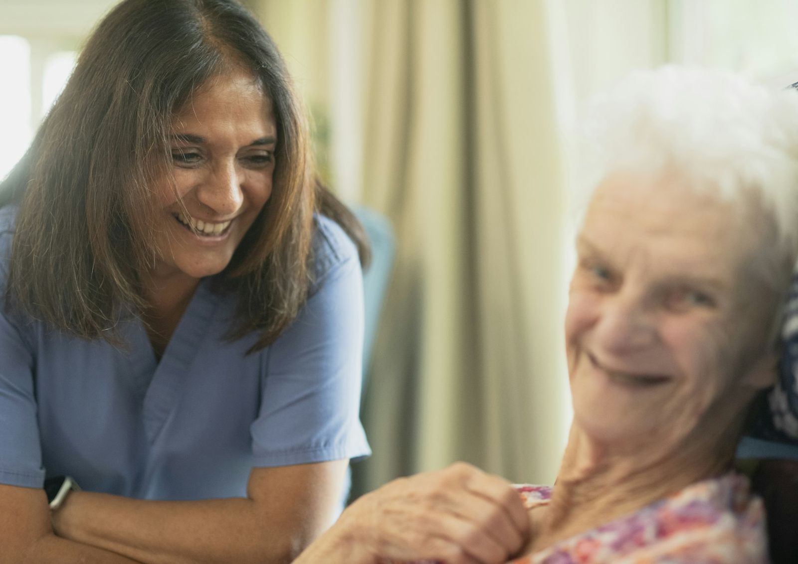 A caregiver sharing a laugh with an older resident